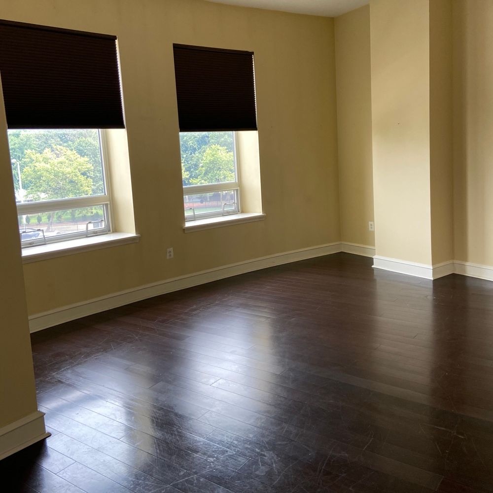 Freshly cleaned room with bright windows and gleaming dark hardwood floors